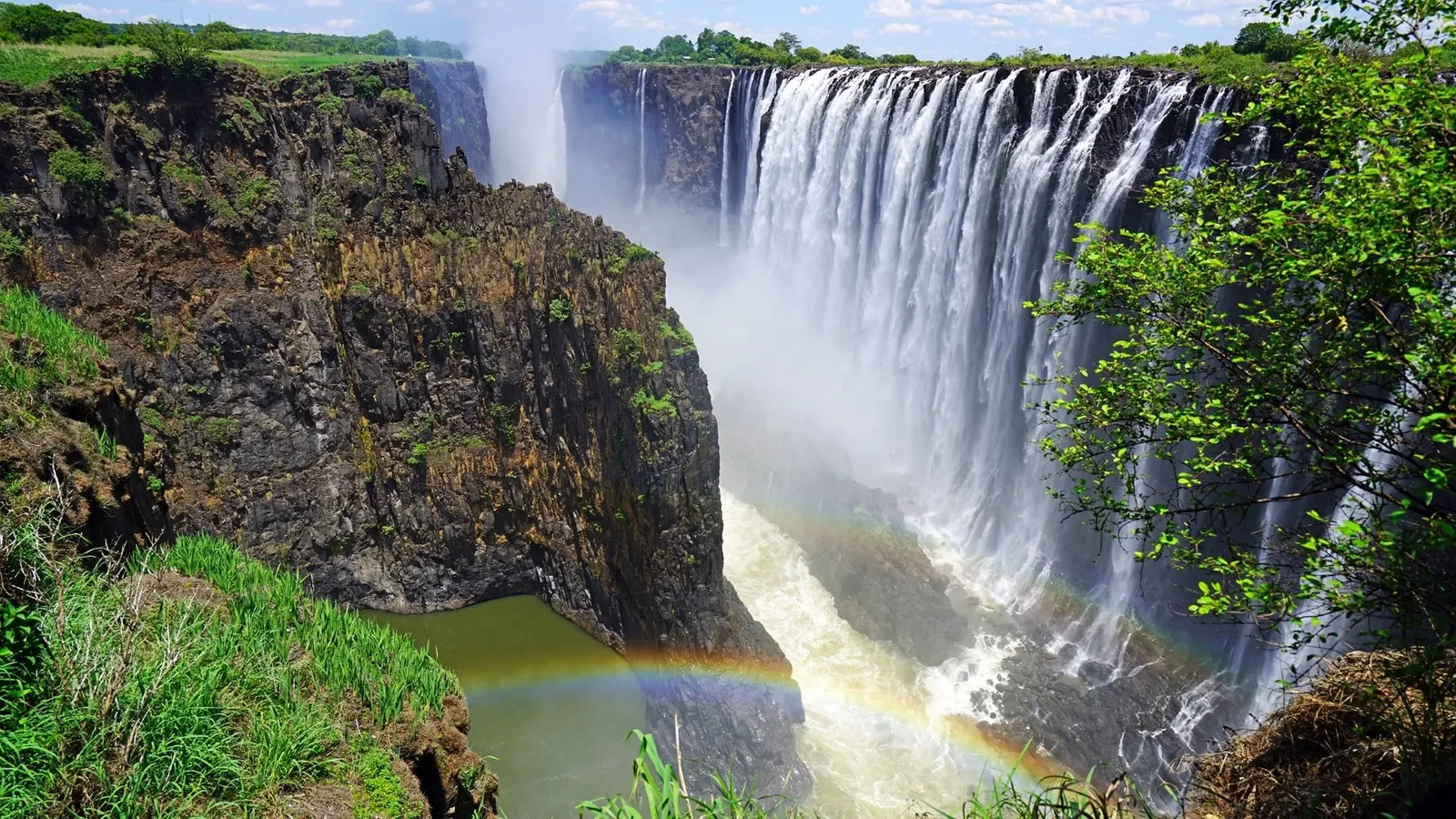 Victoria Falls in full flow, with a rainbow over the gorge
